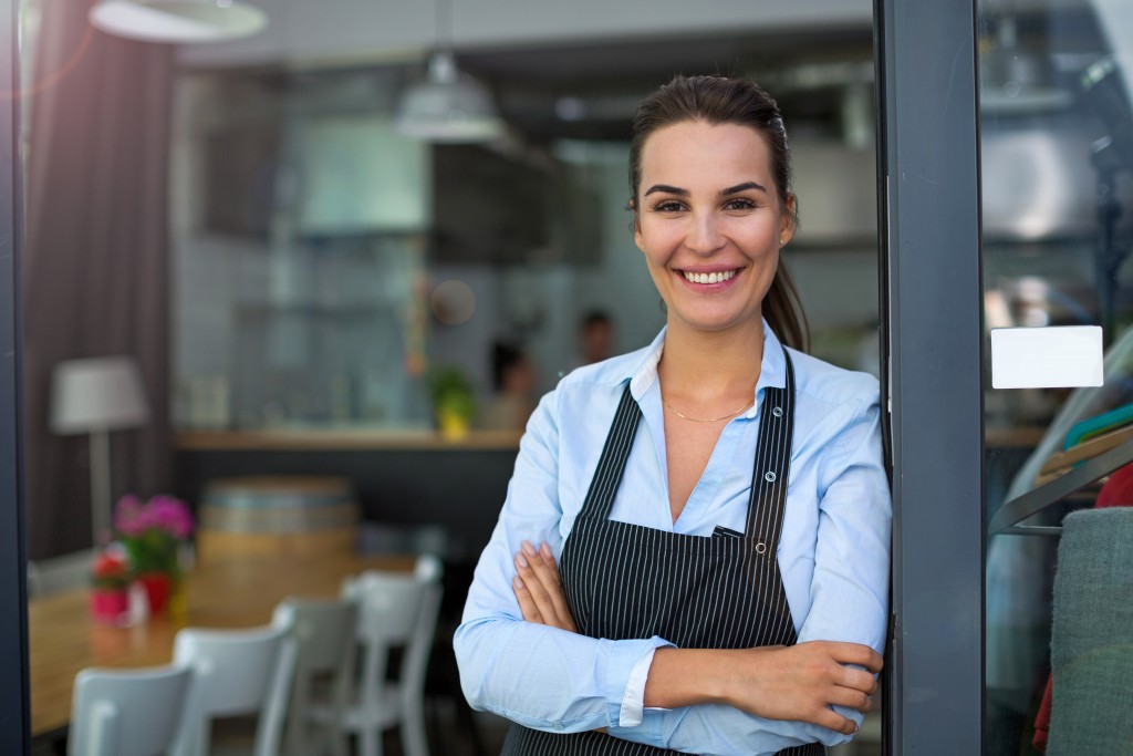 smiling entrepreneur standing at the side of the front door of her restaurant