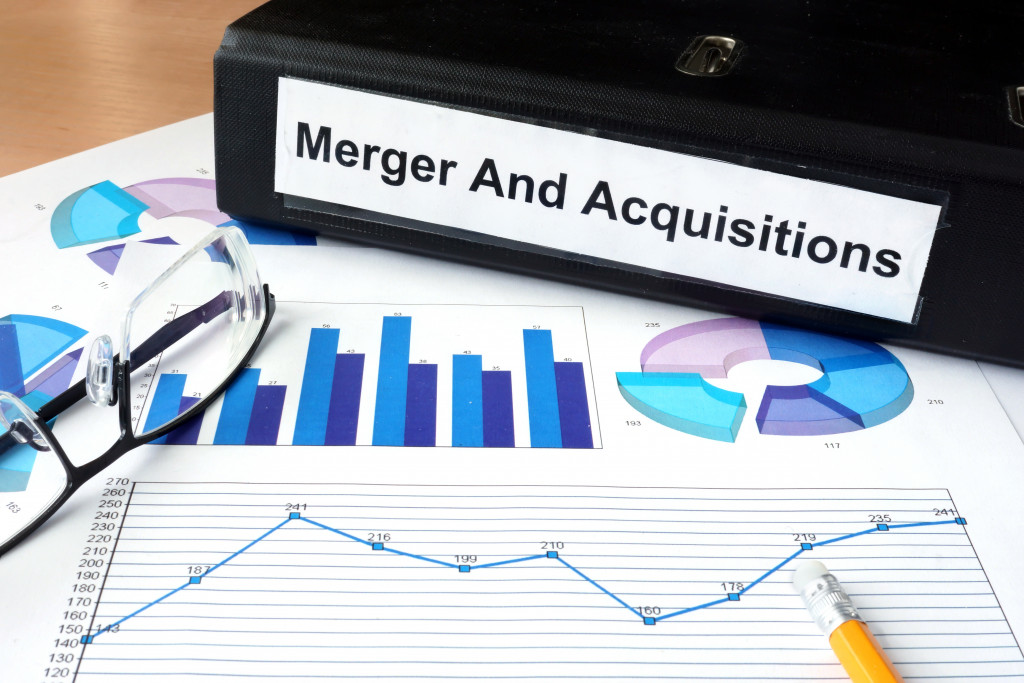 A file folder with merger and acquisitions and financial graphs